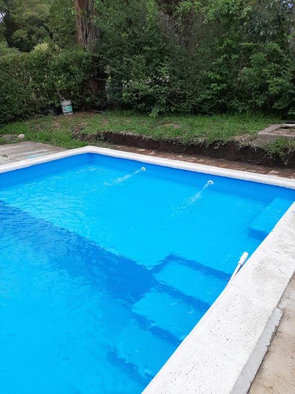 a large blue swimming pool in a yard at Sierras Chicas La Granja in Córdoba
