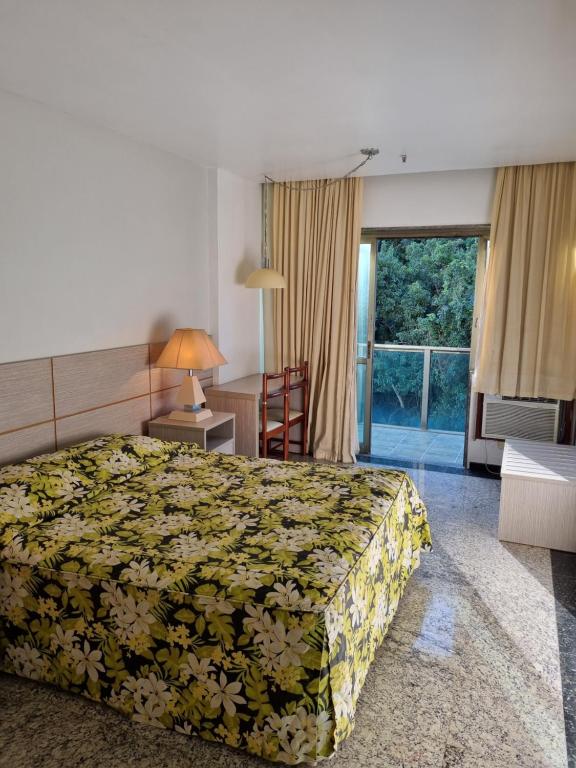 um quarto de hotel com uma cama, uma secretária e uma janela em Royalty Copacabana Hotel no Rio de Janeiro