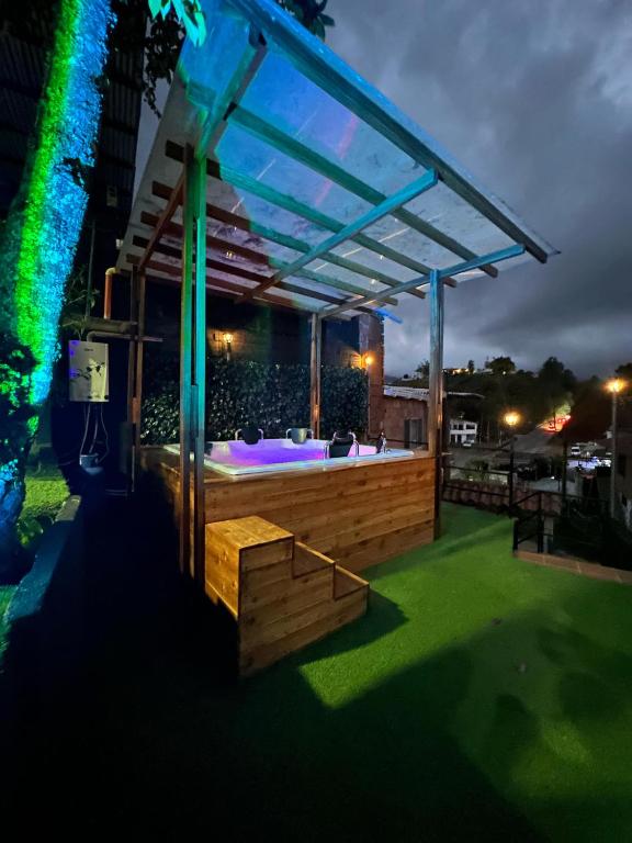 una terraza con bañera de hidromasaje bajo una pérgola por la noche en Hermosa casa de campo el Peñol,Guatapé, en Guatapé
