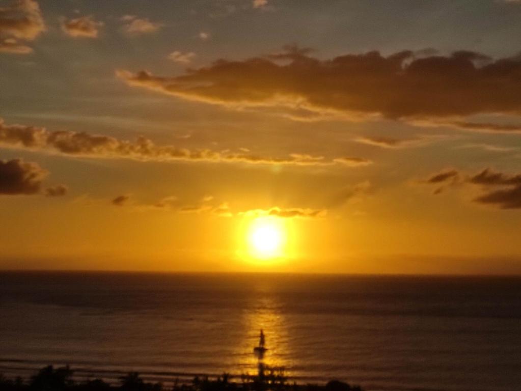 una puesta de sol sobre el océano con un faro en Ty Kaz Dodo, en Saint-Gilles-les-Bains