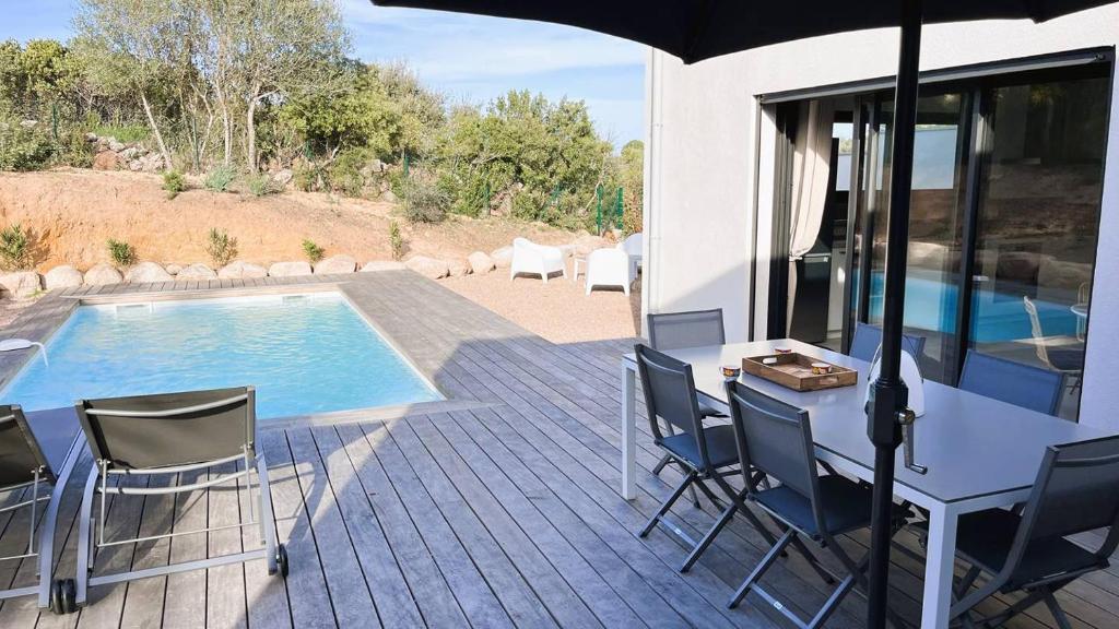 a patio with a table and chairs next to a pool at Villa Copains, 5 pers, piscine chauffée, 5 mn plage in Cirendinu