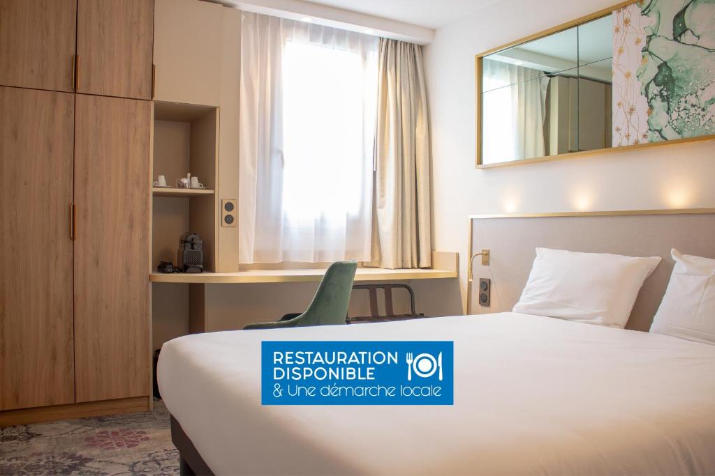 um quarto de hotel com uma cama e um espelho em Brit Hotel Bordeaux Aéroport - Le Soretel em Mérignac