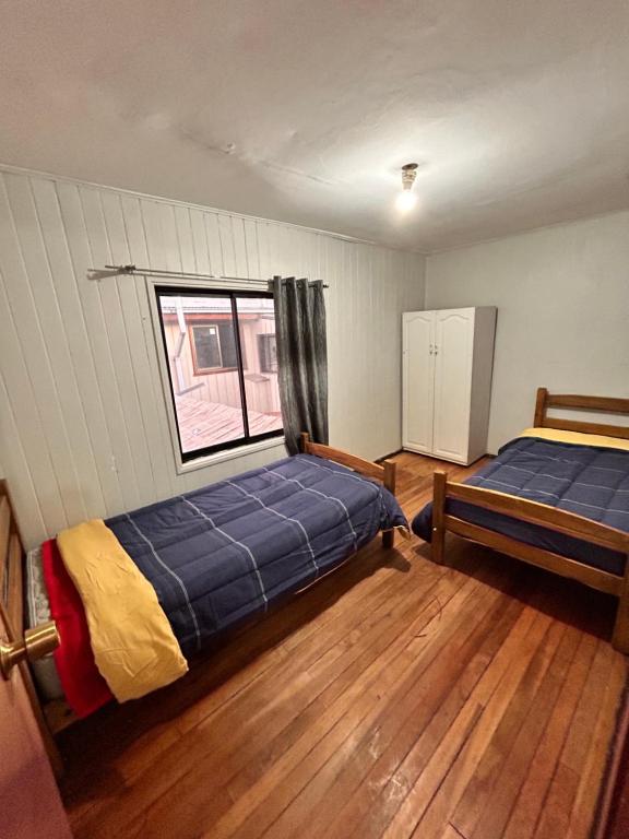 1 dormitorio con 2 camas y ventana en Casa familiar, en Temuco