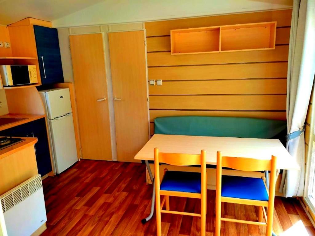 eine kleine Küche mit einem Tisch und zwei Stühlen in der Unterkunft Bungalow charmant à Saint-Chéron avec piscine partagée in Saint-Chéron