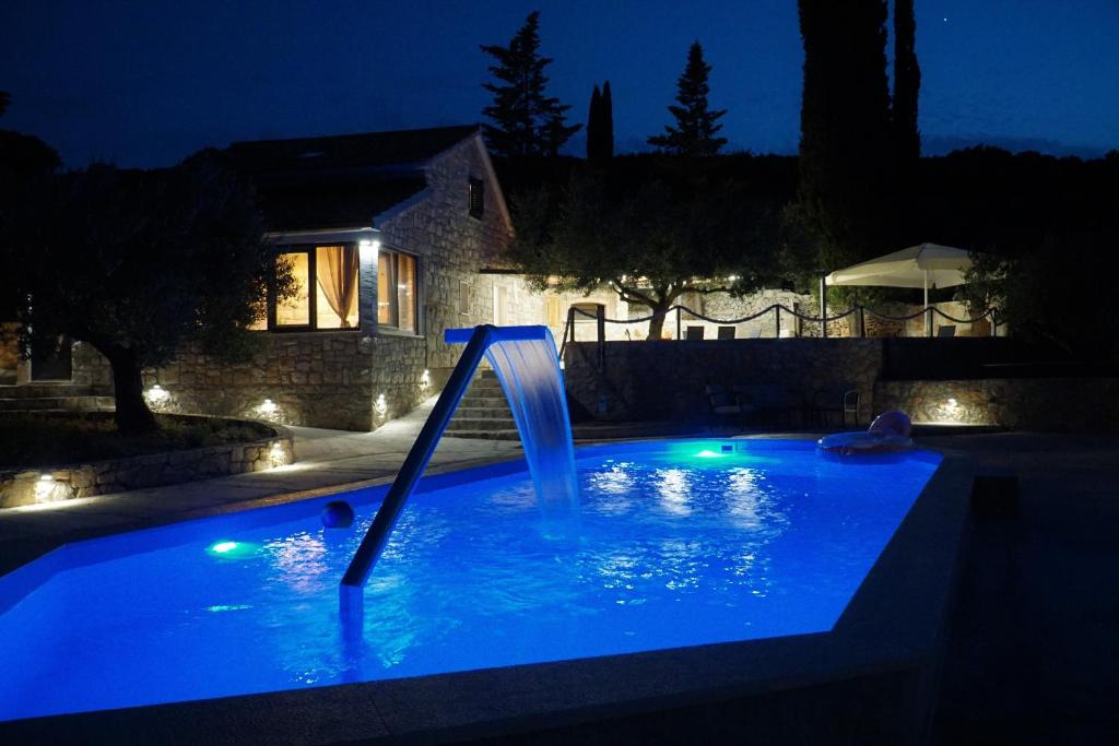 a pool with a water slide in a yard at night at Villa Broč in Postira