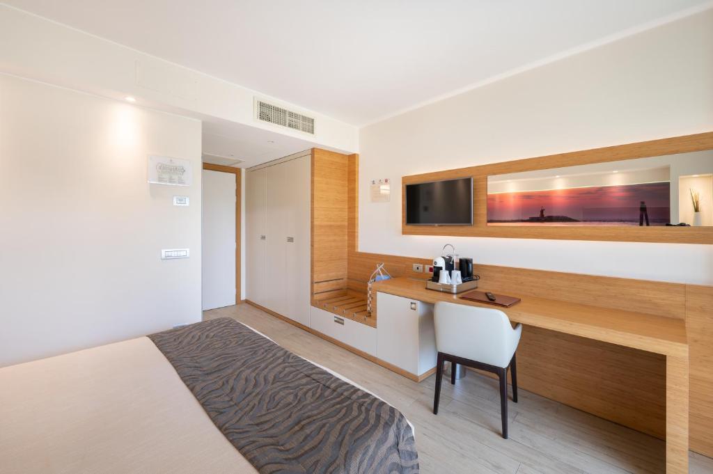 a bedroom with a bed and a desk and a television at Laguna Park Hotel 4Superior in Bibione