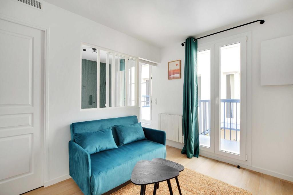 a blue couch in a living room with a window at Modern and functional apartment Ménilmontant in Paris