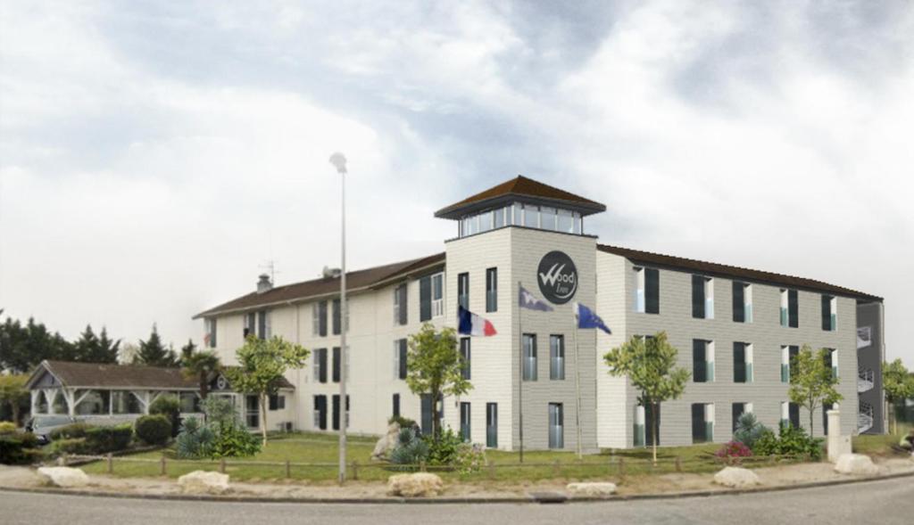 a large white building with flags in front of it at Hotel Wood Inn Bordeaux Aéroport in Mérignac