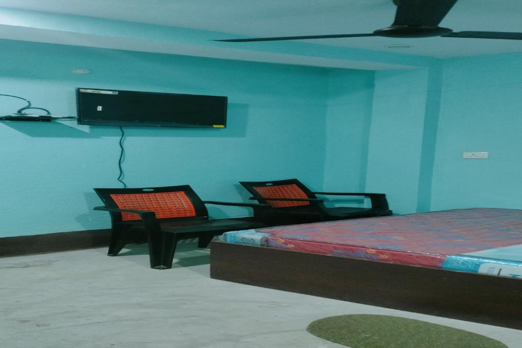 a bedroom with two chairs and a tv on the wall at SPOT ON Pushpanjali Guest House in Patna