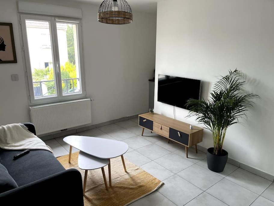 sala de estar con sofá y TV en Espace privé 35 m2 à 15 min de Paris en Groslay