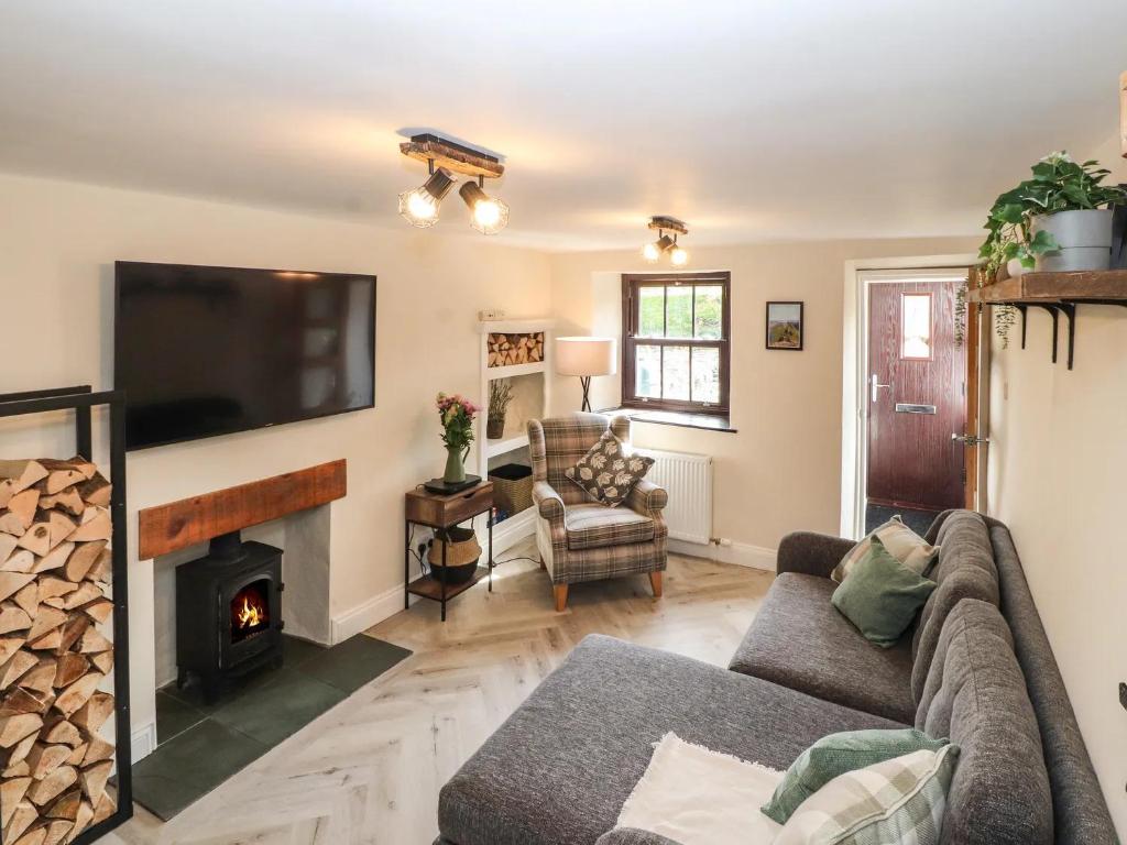 - un salon avec un canapé et une cheminée dans l'établissement Fellside Cottage, à Shap