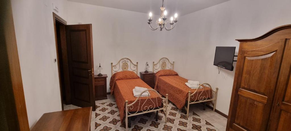 a room with two beds and a table and a chandelier at Arcaloro Resort Rooms Ghiro in SantʼAngelo di Brolo