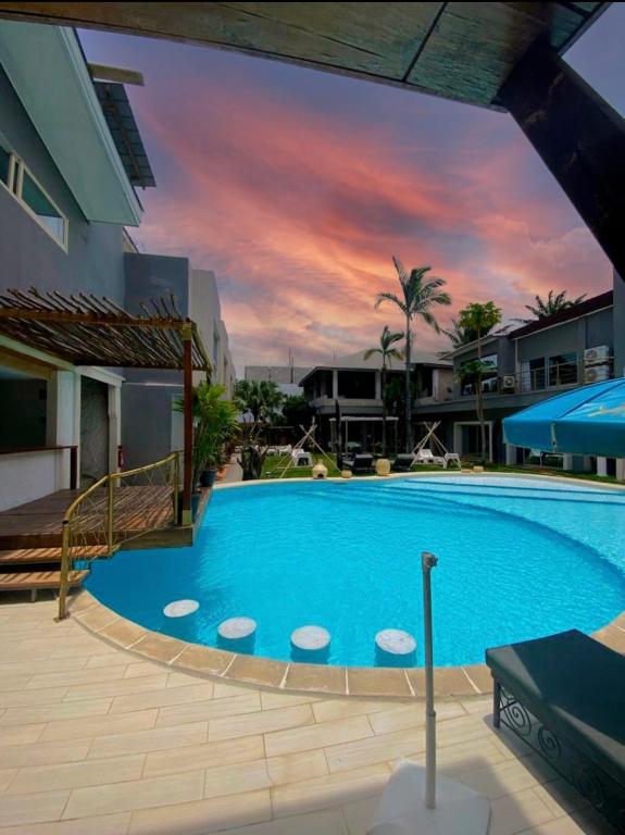 a large blue swimming pool with a sunset in the background at Hôtel atlantys in Abidjan