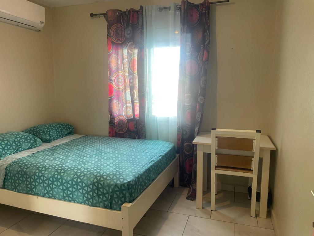 1 dormitorio con cama, mesa y ventana en Location chambres Mtsapéré Maevantana sur Mamoudzou Mayotte chez Zam, en Mamoudzou