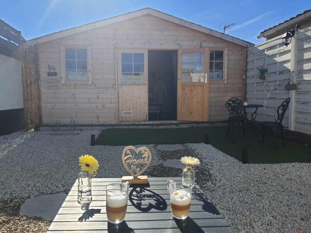 un patio trasero con una mesa con bebidas y flores en Le temps suspendu en Trèbes