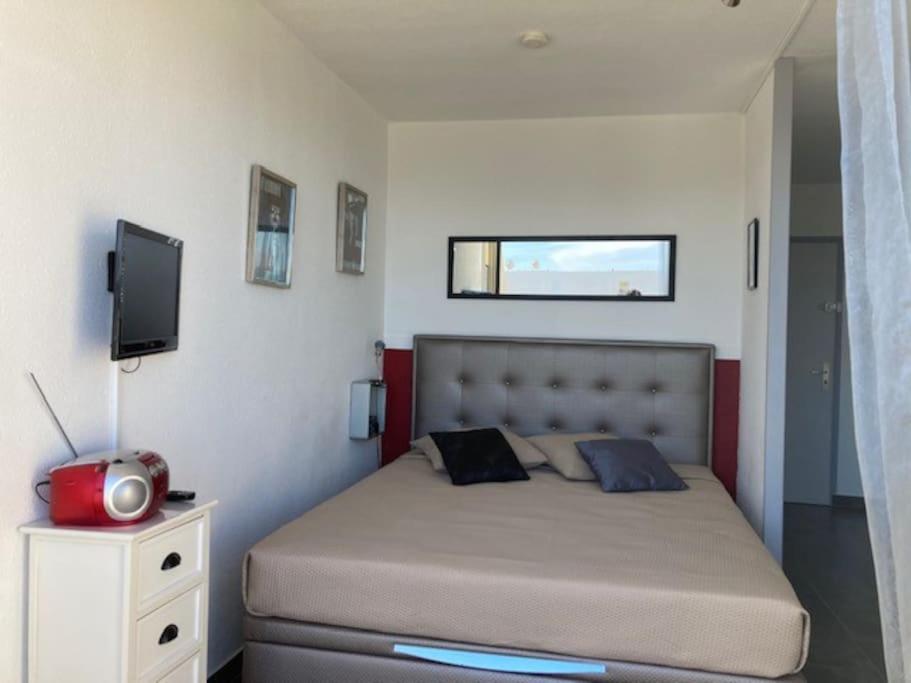 - une chambre avec un lit et une télévision dans l'établissement Studio 2, Héliopolis D au village naturiste, au Cap d'Agde