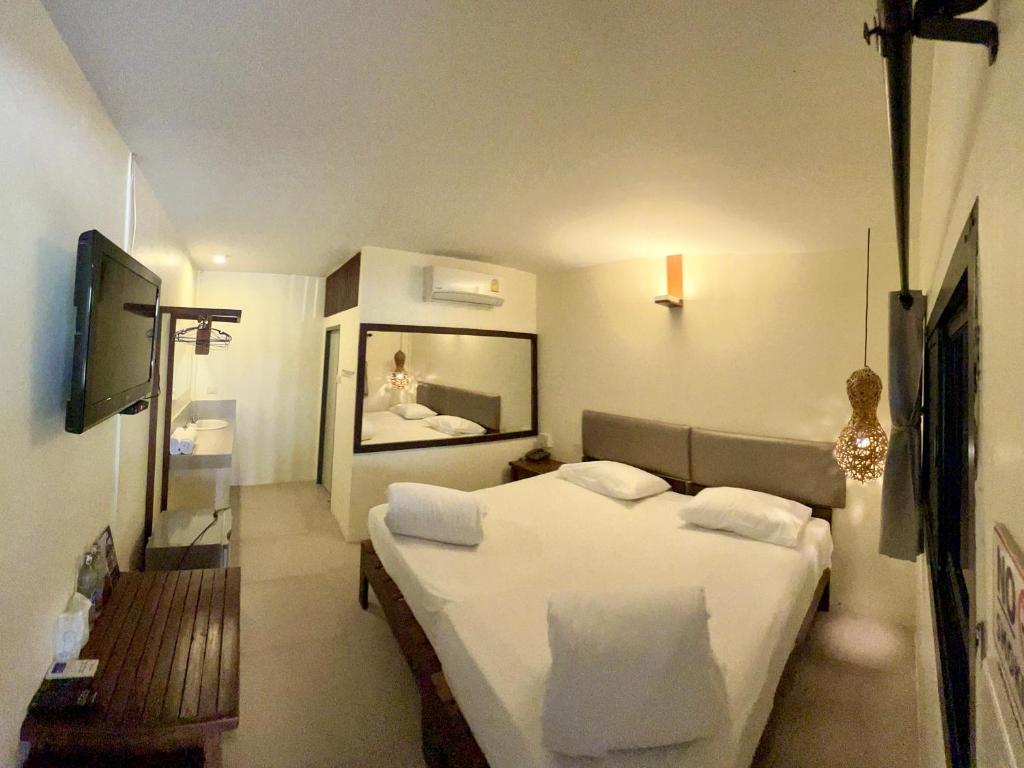 a bedroom with a white bed and a television at Ngeeb bed and EV station in Chiang Rai