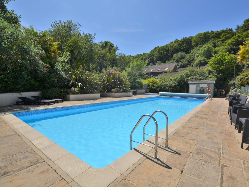 a large swimming pool with chairs and trees at 1 Bed in Charmouth 41890 in Charmouth