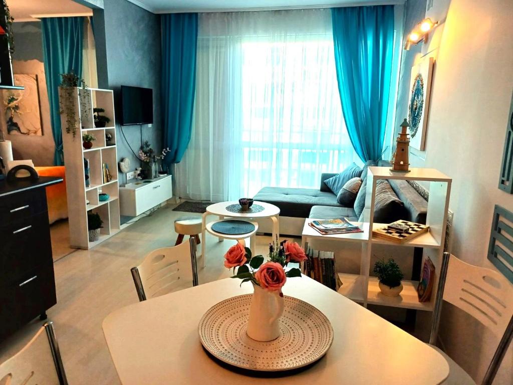 uma sala de estar com uma mesa com um vaso de flores em Апартамент BLUE SUMMER - уют, близо до морето em Burgas