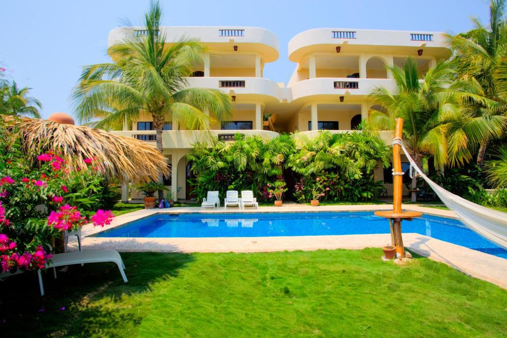 a resort with a swimming pool and a hammock in the yard at Las Turquezas in Puerto Escondido