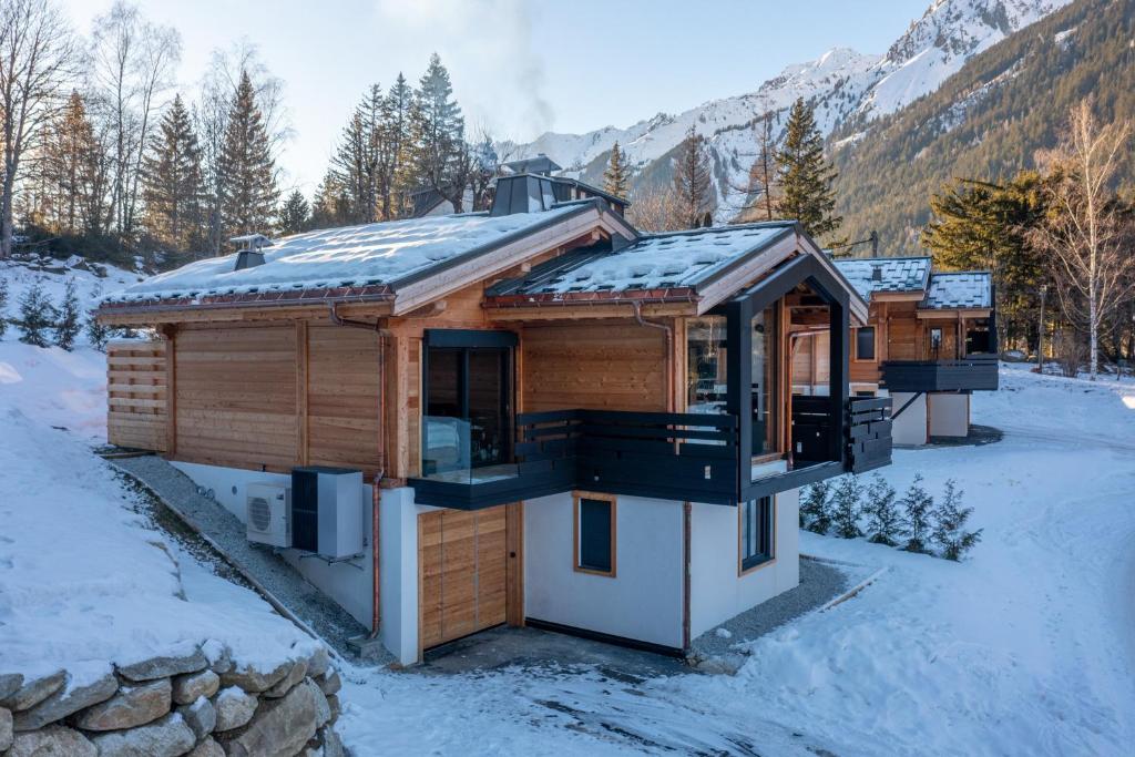 a log cabin in the snow with mountains in the background at Chalet Seven Summits - Pool - Sauna - Jacuzzi - By Cozee Rentals in Chamonix-Mont-Blanc