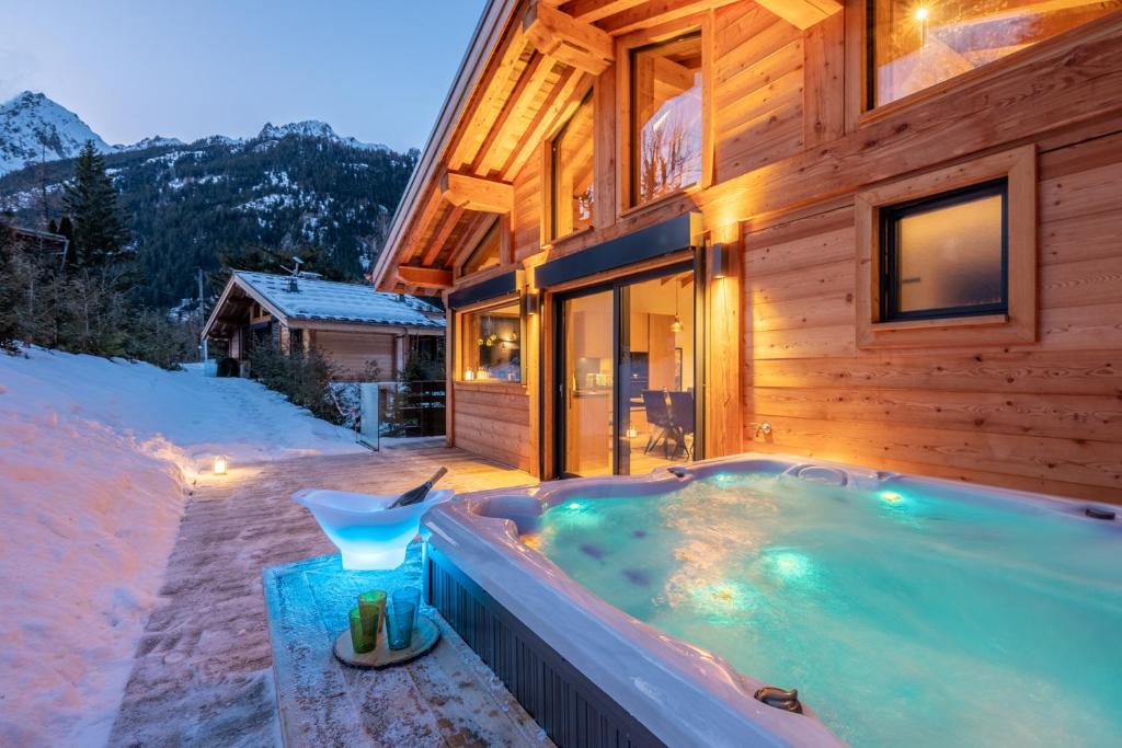 d'un bain à remous en face d'une maison dans la neige. dans l'établissement Chalet Seven Summits - Pool - Sauna - Jacuzzi, à Chamonix-Mont-Blanc