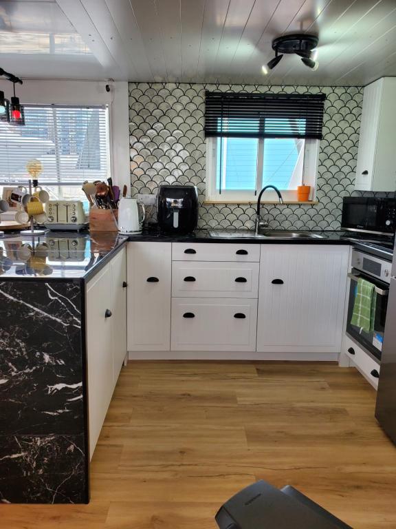 una cocina con armarios blancos y encimeras negras en JASMINE CORAL JAY Boutique Boatel Ocean Village, en Gibraltar