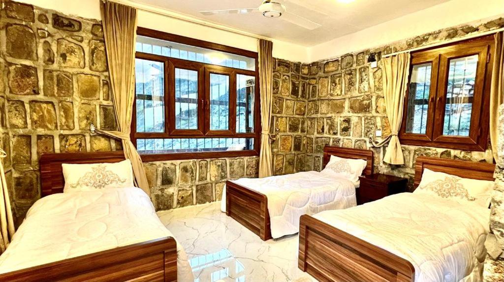 a bedroom with two beds and a stone wall at Guest house baldsayt in Bilād Sayt