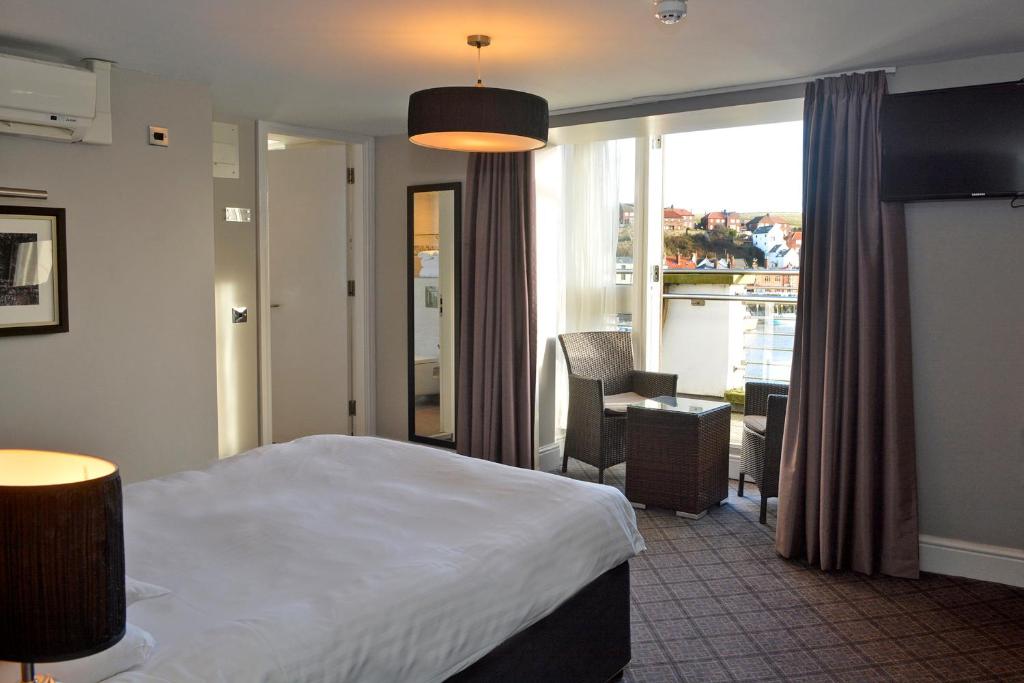 ウィットビーにあるThe Angel Hotel Wetherspoonのベッド、デスク、窓が備わるホテルルームです。