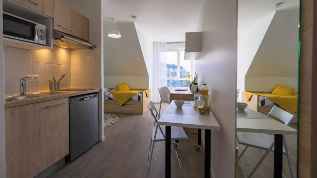 - une cuisine avec une table et des chaises jaunes dans la chambre dans l'établissement NEMEA APPART ETUD ROUEN CONSTANTINE, à Rouen