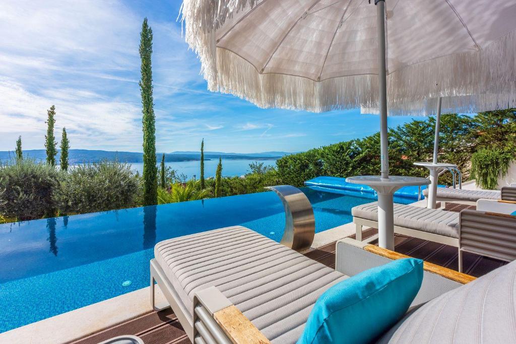 Villa con piscina y patio con sombrilla en Luxusvilla mit Infinity-Pool, Wellnessbereich, 1 km zum Strand, en Crikvenica