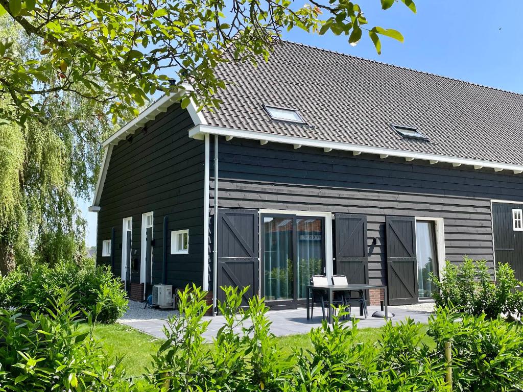 een zwart huis met een tafel ervoor bij Chezeehoeve - Wemeldinge in Wemeldinge