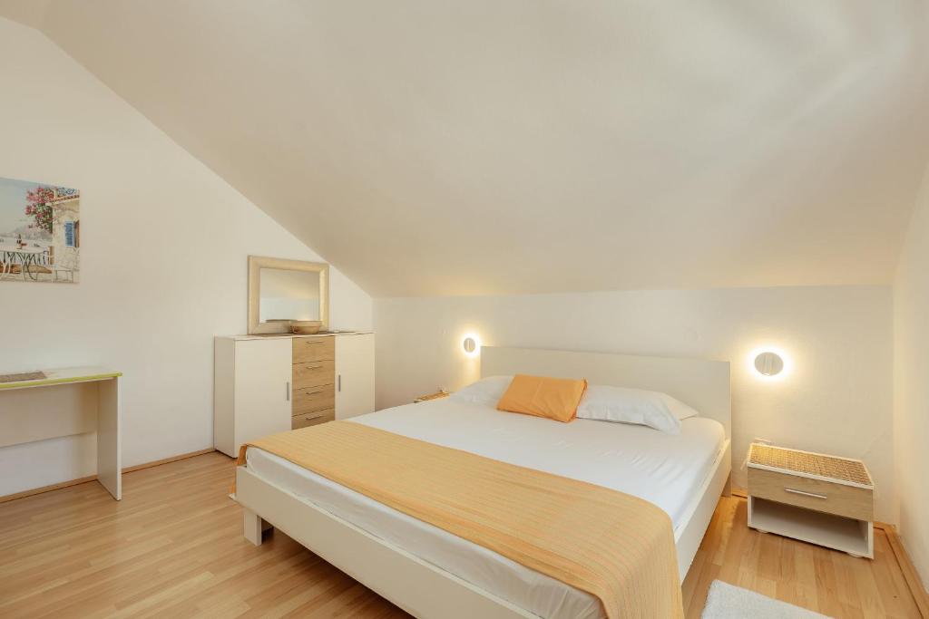 a bedroom with a white bed with an orange pillow at Suberic Apartments in Herceg-Novi