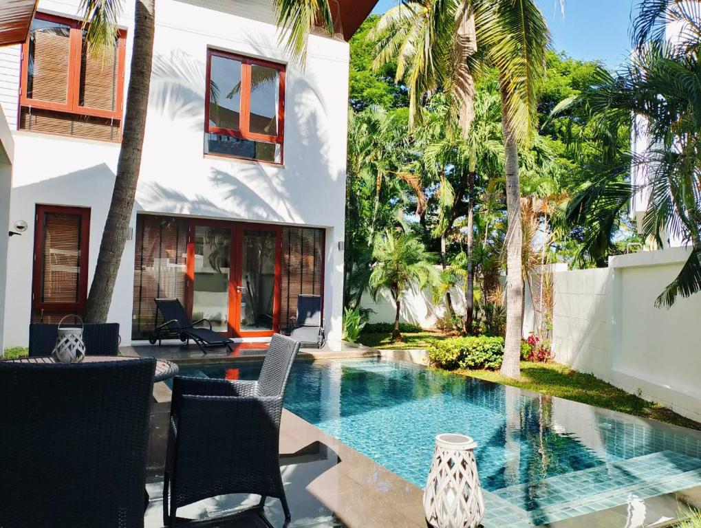 a swimming pool in the backyard of a house with palm trees at Pranaluxe Pool Villa Holiday Home in Pran Buri