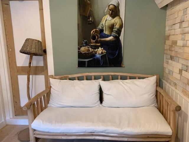un banco de madera con una pintura de una mujer en Appartement 't Souterrain en Zandvoort