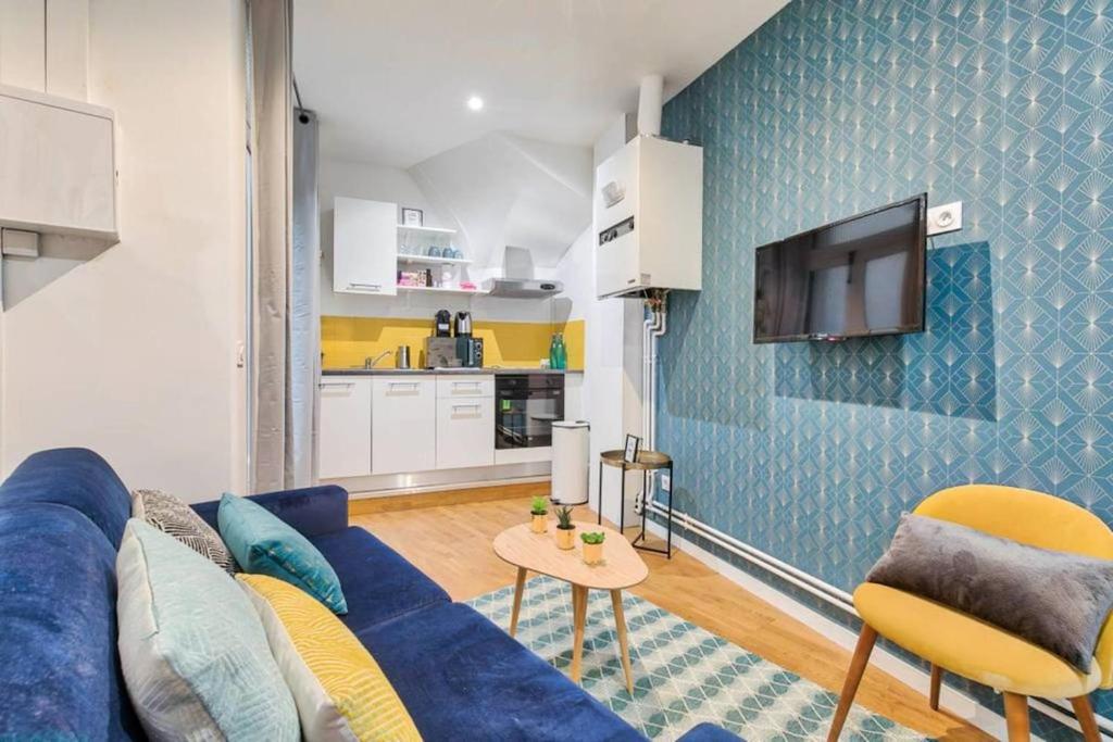 un salon avec un canapé bleu et une télévision dans l'établissement Appartement Familial proche Saint-Lazarre - 6P, à Paris