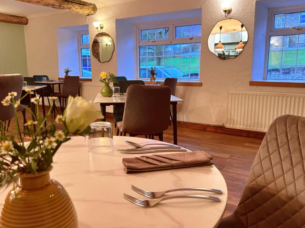 a dining room with a table and chairs and windows at Penybont Restaurant + Inn in Carmarthen
