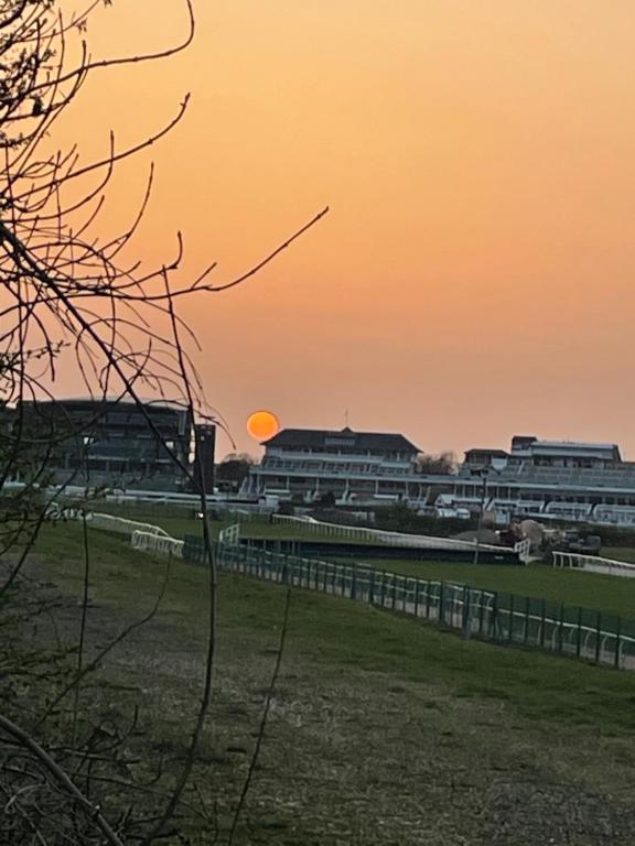 um pôr-do-sol sobre um campo com uma cerca e edifícios em Aintree Grand National Home em Aintree