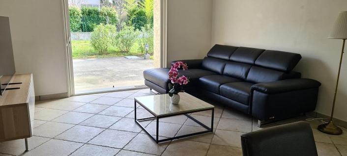 un soggiorno con divano in pelle nera e tavolo di Le Rouge Gorge à 12 minutes d'Eurexpo a Genas