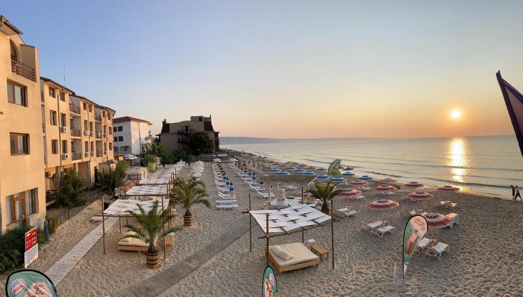 Palma Beach Hotel في كرانيفو: شاطئ به كراسي ومظلات والمحيط