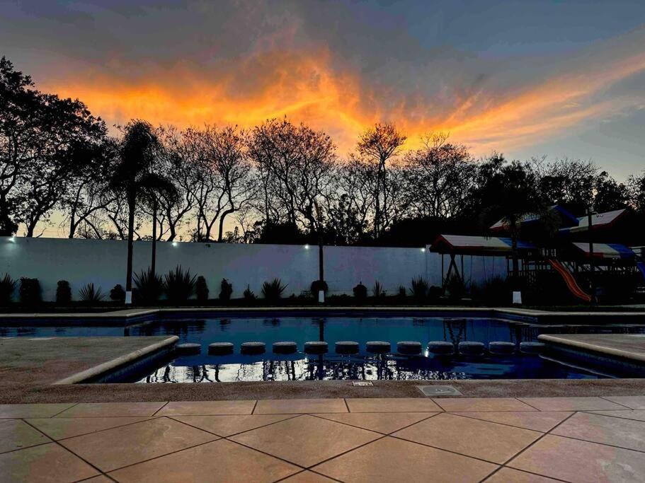 einen Pool mit Sonnenuntergang im Hintergrund in der Unterkunft La casa de los colibríes in Hacienda Blanca