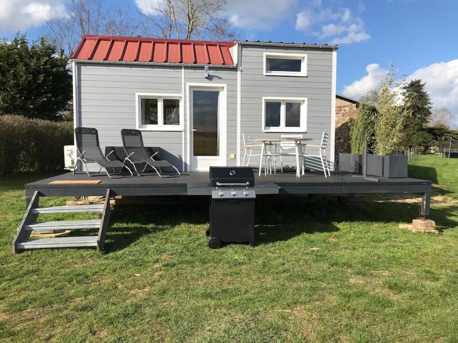 Tiny house à la ferme près Paris et center parcs. في Boissy-sur-Damville: منزل صغير على رصيف مع كراسي وشواية