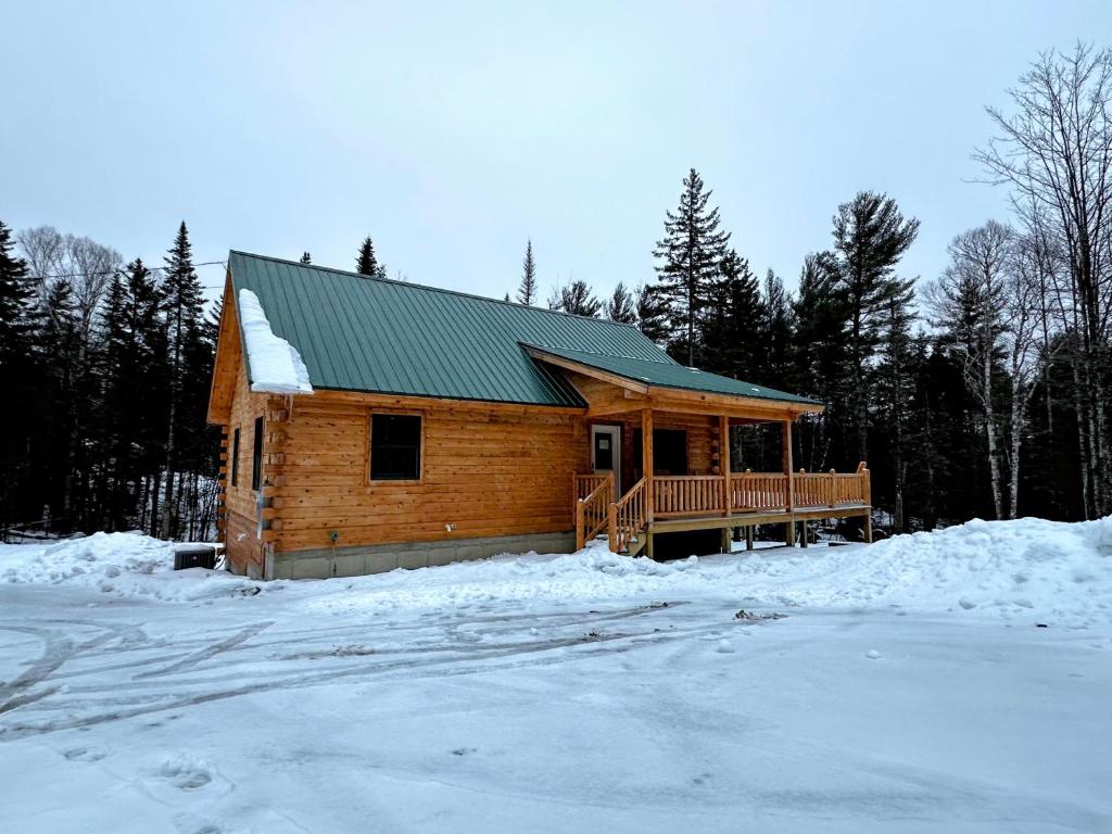 a log cabin with a deck in the snow at 65PT New Log Cabin in Private Setting. Hot tub. Gym/Pool Access! in Twin Mountain
