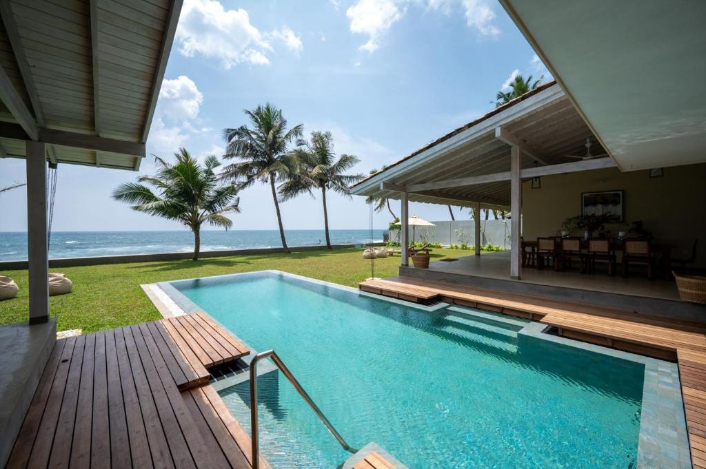 a swimming pool next to a house with the ocean at Nil Ralla in Talpe