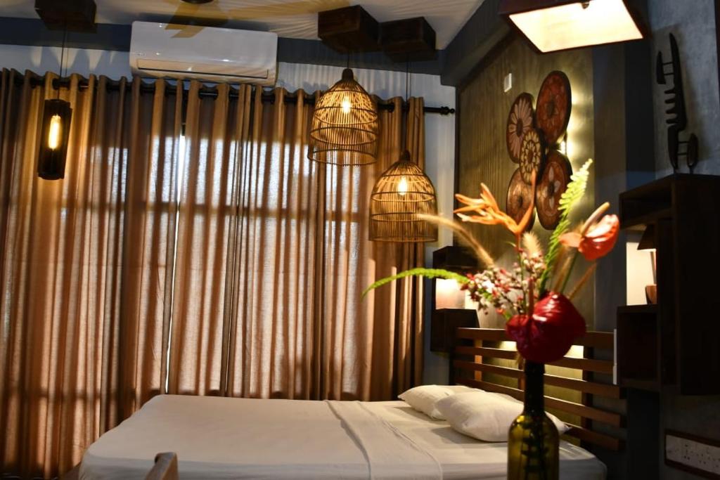 1 dormitorio con 1 cama y un jarrón con flores en Guruwaththa Eco Lodge en Hikkaduwa