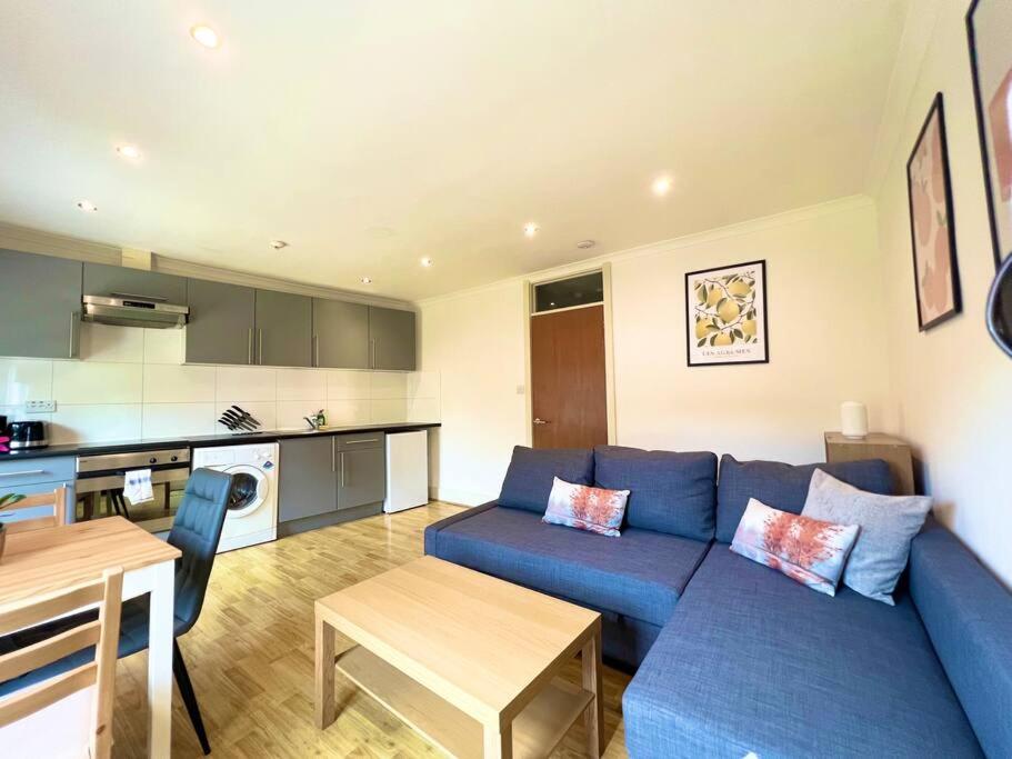 a living room with a blue couch and a kitchen at Crouch End- 1 Bed Apartment in London