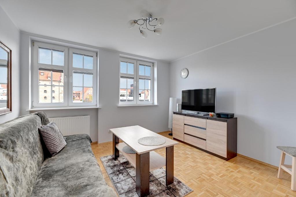 a living room with a couch and a tv at Warzywnicza - Motłava View by Grand Apartments in Gdańsk