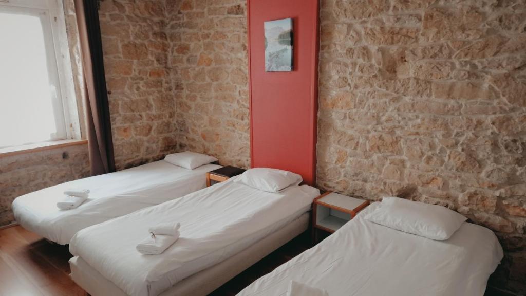 three beds in a room with a brick wall at Hôtel Hermance in Bellegarde-sur-Valserine