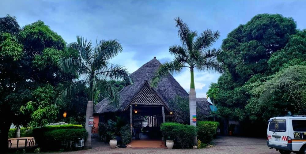 een gebouw met een puntdak met palmbomen bij splash resort hotel in Mtwara