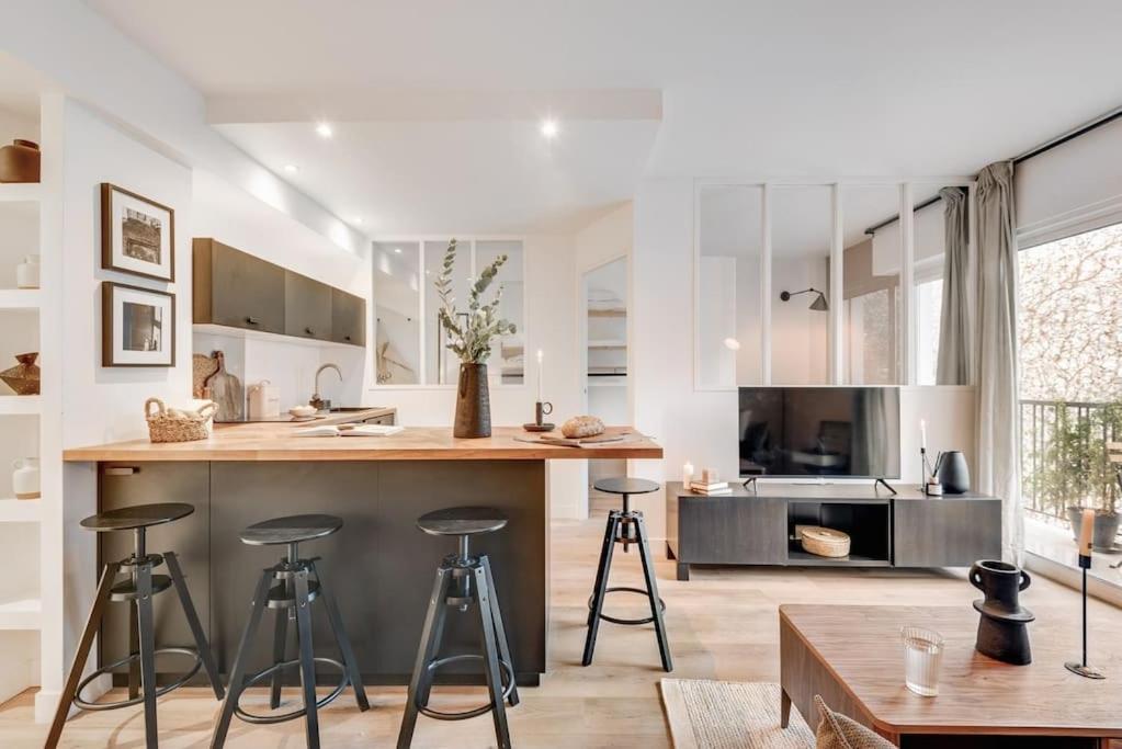 une cuisine avec tabourets de bar et des placards blancs dans l'établissement Monceau - 1 chambres à Batignolles, à Paris
